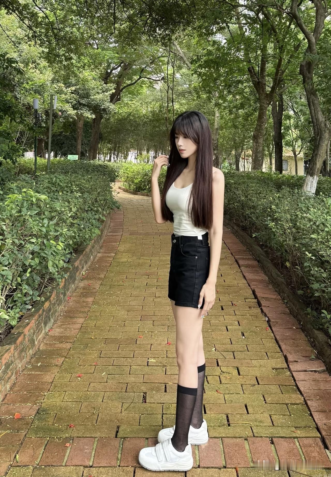 夏日清新穿搭，绿意盎然的小径上，白色背心+黑色短裙，搭配白色运动鞋，轻松自在。