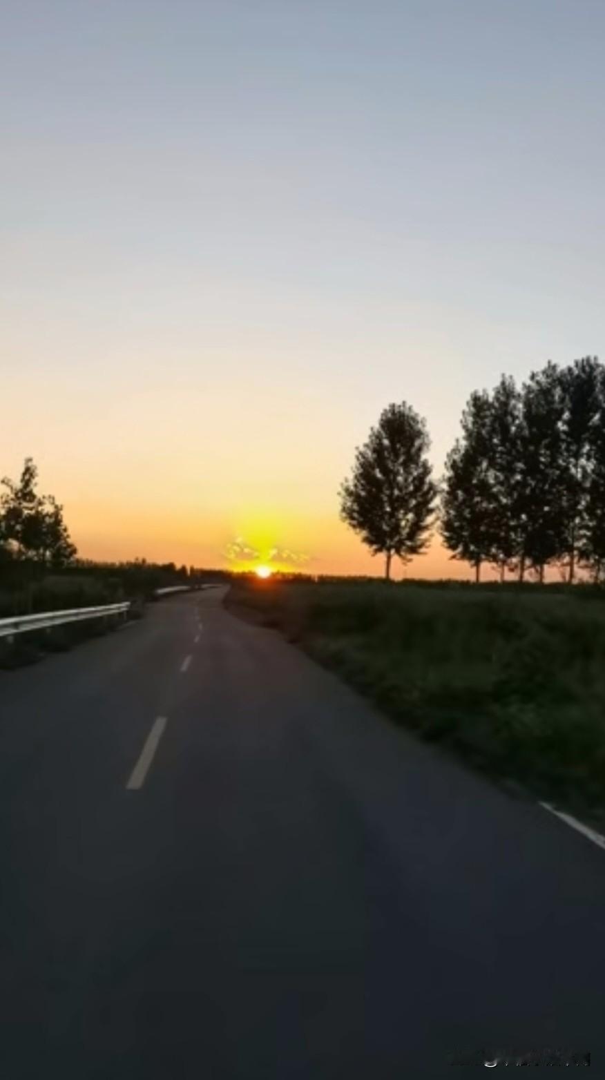 分享一张拍摄到的晚霞图片落日缓缓垂落在道路的尽头，漫天晚霞晕开温柔的橘金色，把乡