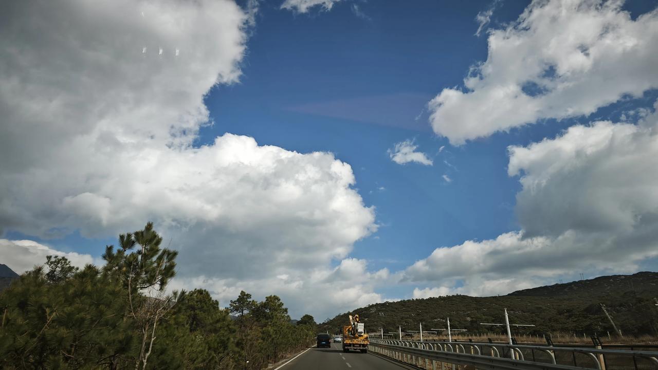 分享一下你随手拍下的照片车轮碾过风的纹路，云团在头顶铺展成柔软的棉絮。远山与松林
