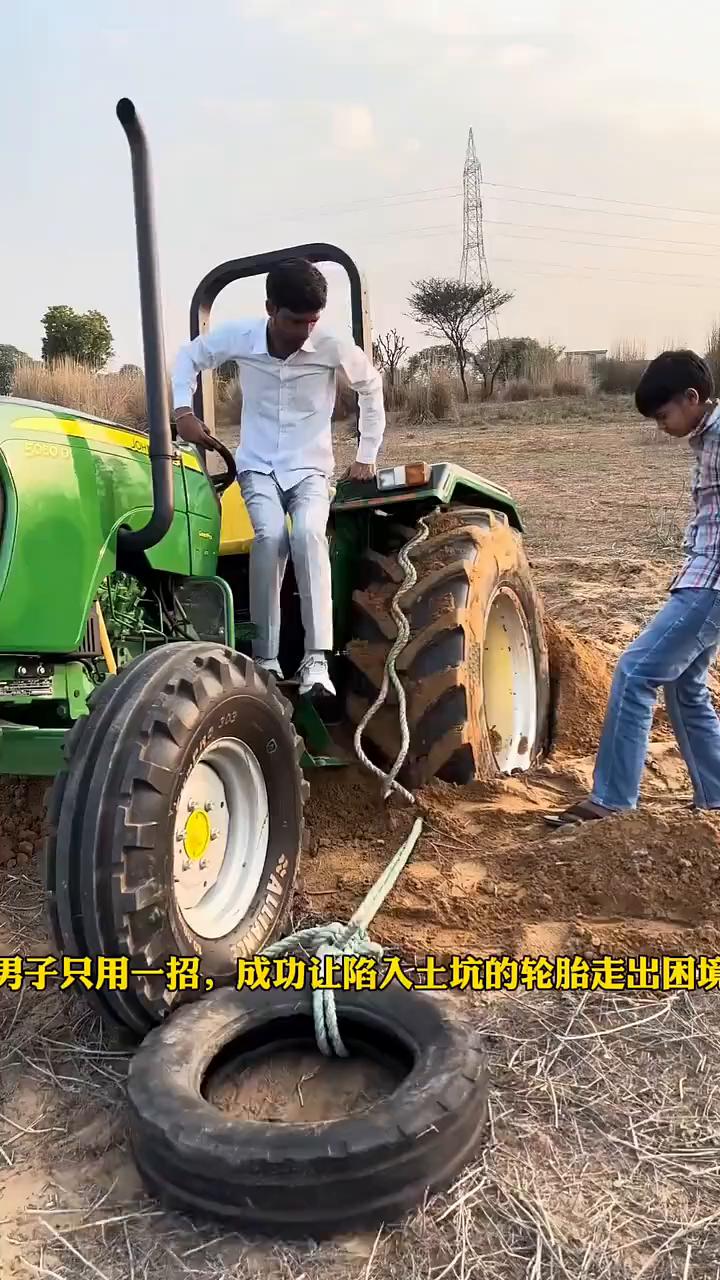 男子只用一招成功让陷入土坑的轮胎走出困境。只见他将一个破旧轮胎绑在车轮上，之后启
