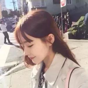 在阳光明媚的街头，温柔的女孩低头微笑，洋溢着幸福。