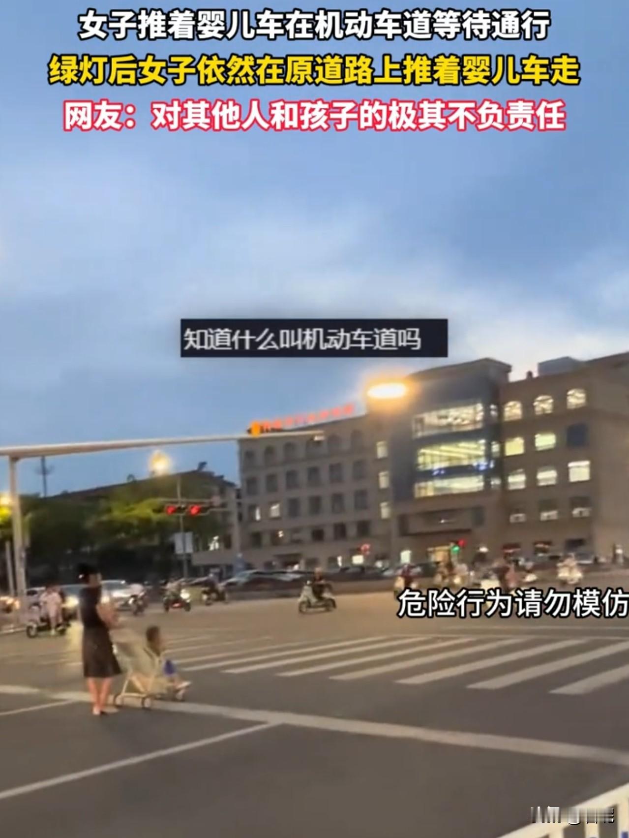 一女子推着婴儿车在机动车道等待通行，但是绿灯后女子依然在原道路上推着婴儿车前进。