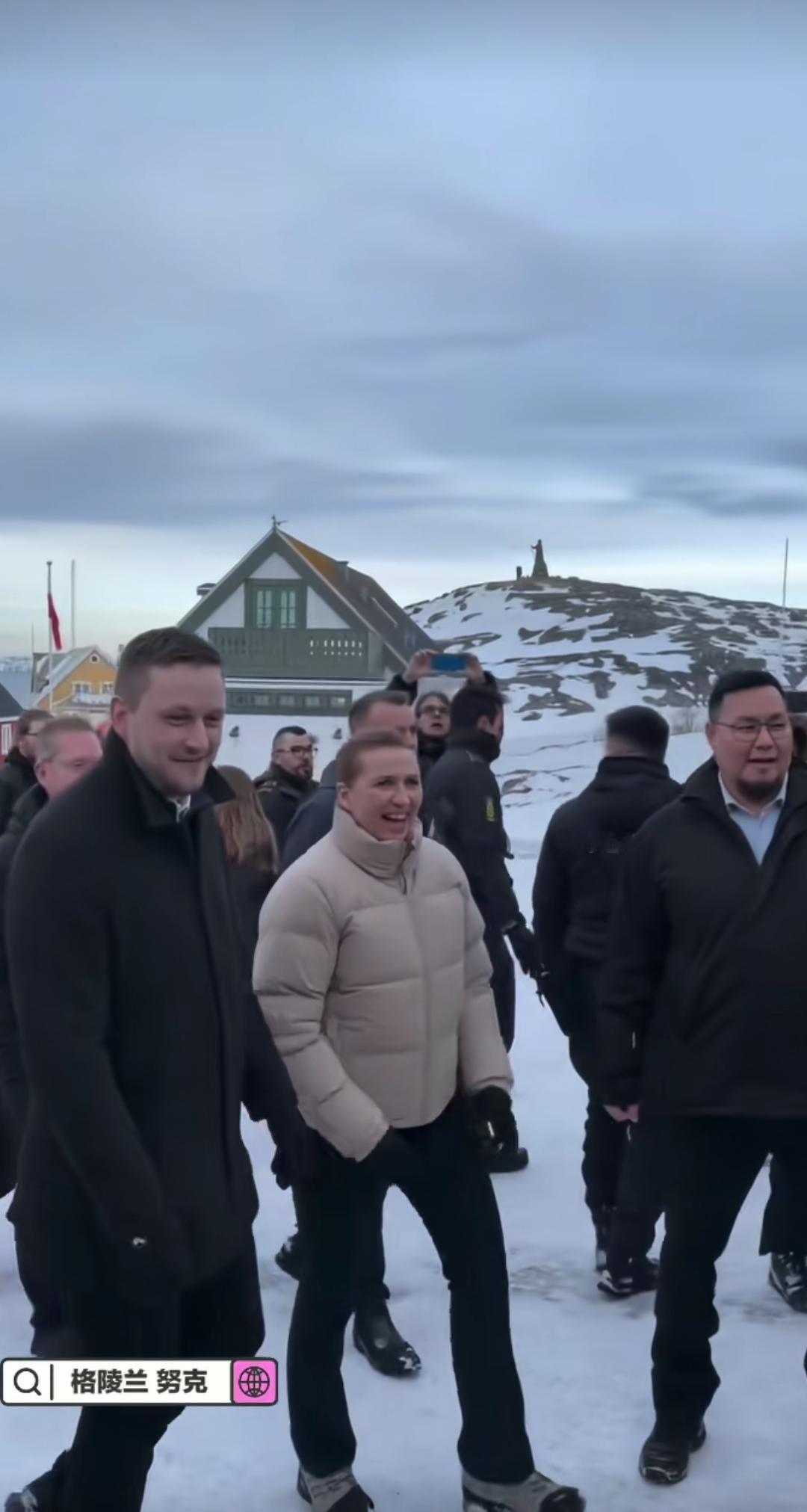 丹麦首相身穿暖色羽绒服，在格陵兰的冰雪中与村民握手。这看似温暖的“家常访问”，实