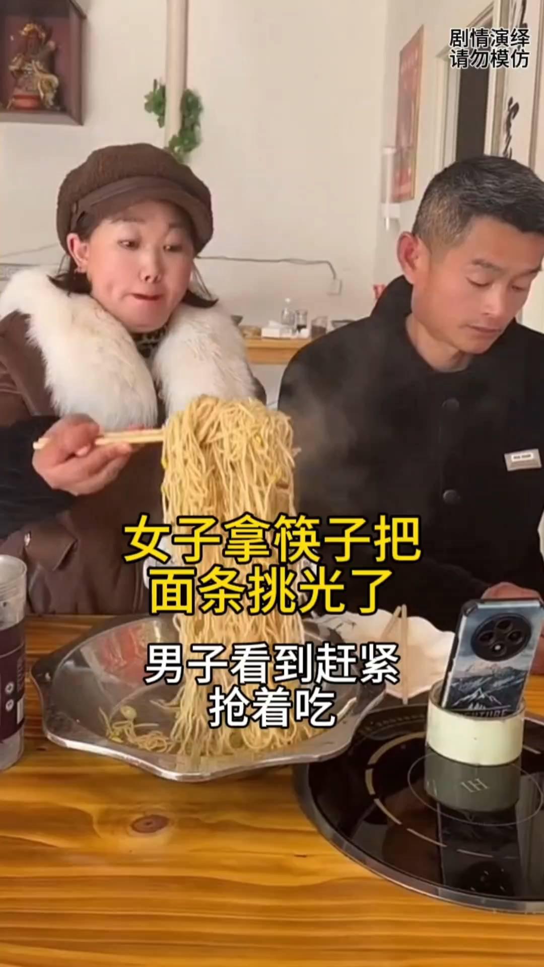 女子拿筷子把面条挑光了，男子看到赶紧抢着吃。
夫妻两个准备吃面，这时旁边丈夫在剥