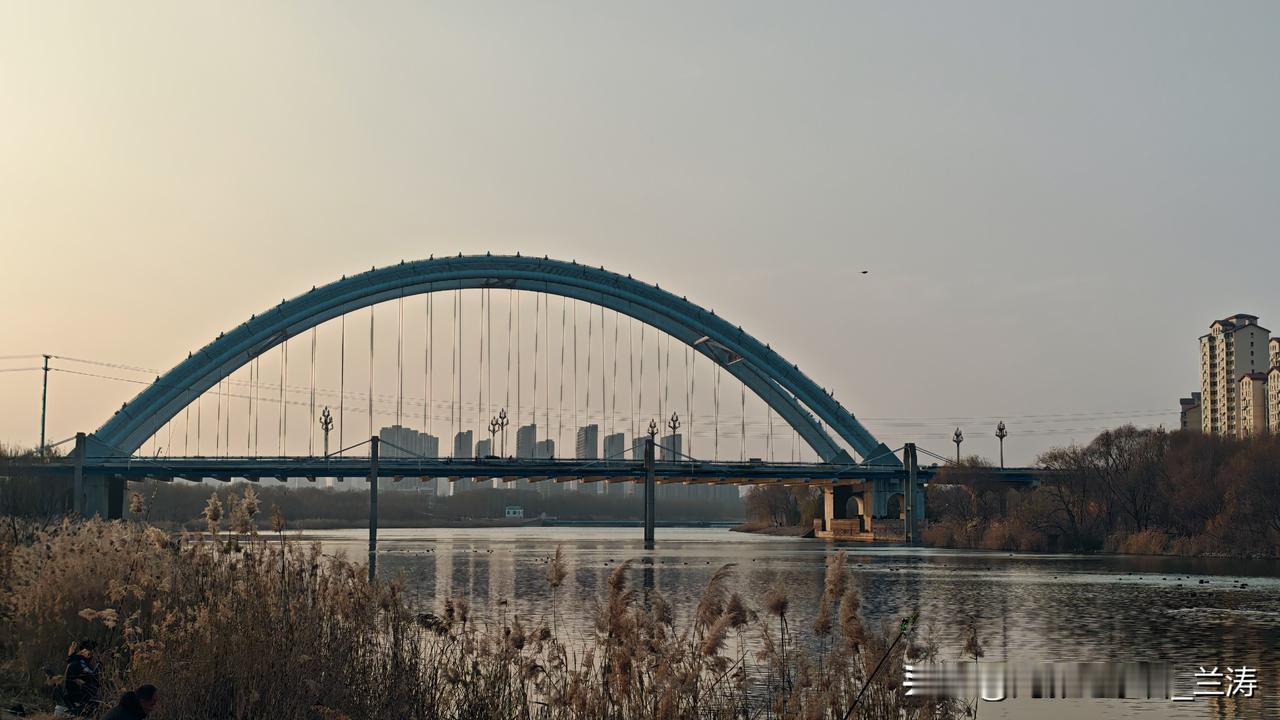 冬至时节，七里河畔寒风轻拂。钢铁路大桥横跨其上，如巨龙卧波。桥下，河水悠悠流淌，