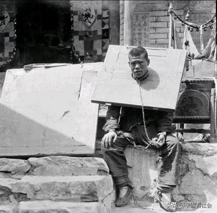 清末民初，一个犯人戴着枷锁眼神呆滞的坐在门口等侍官府发落。
他身上戴的这种枷锁是