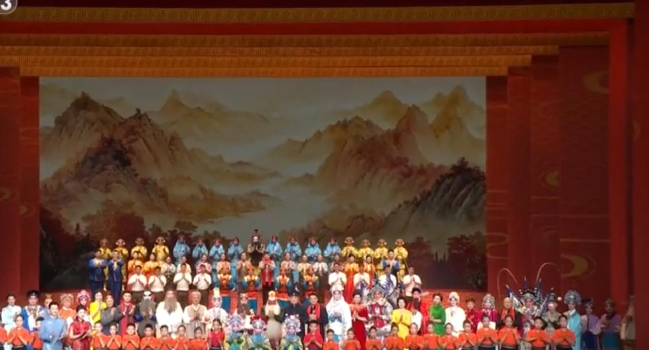 第一张图中，戏曲表演者们身着缤纷戏服齐聚舞台，背景是水墨山水画卷，红框舞台与山水