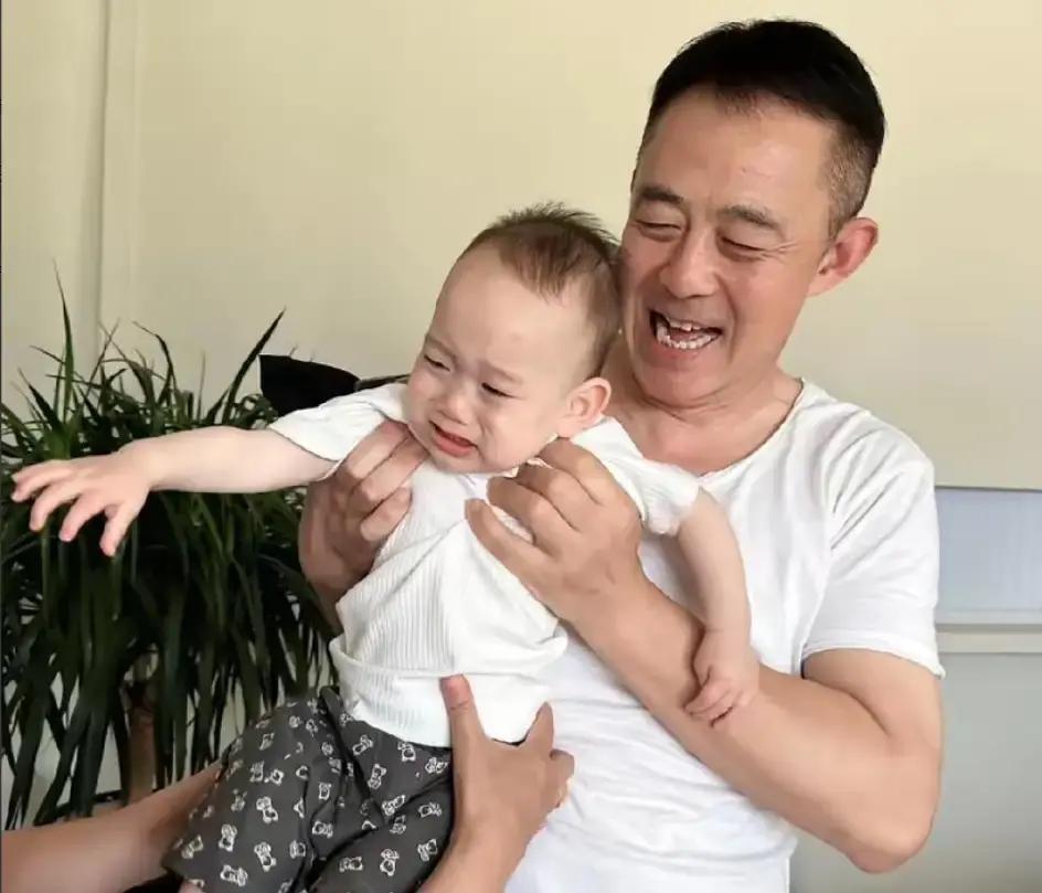 侯勇在社交账号上发了老母亲抱着大孙子的照片，而在十多年前的华表奖领奖台上，他手里
