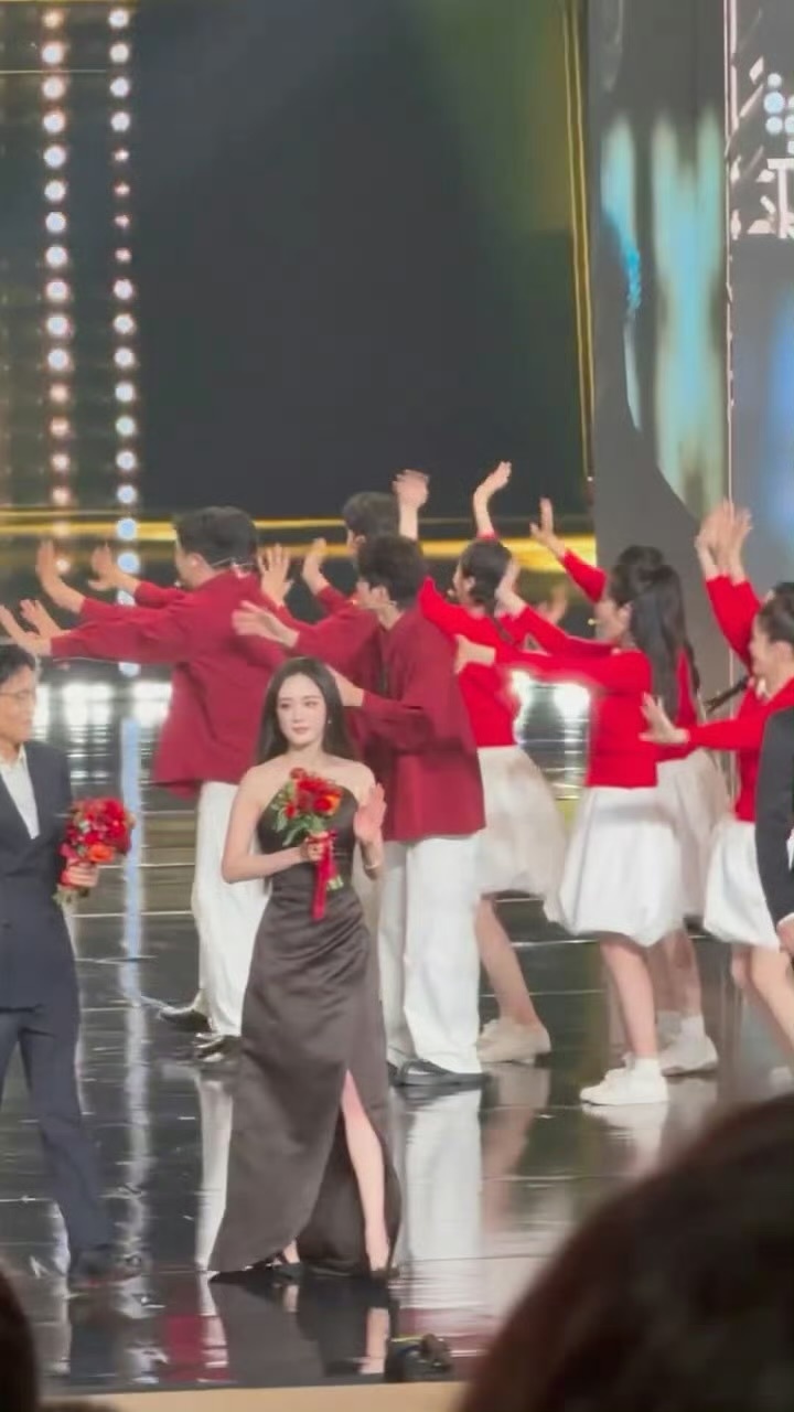 中国电视剧年度盛典上的杨幂，身穿露肩黑色礼裙捧着花和大家一起出现