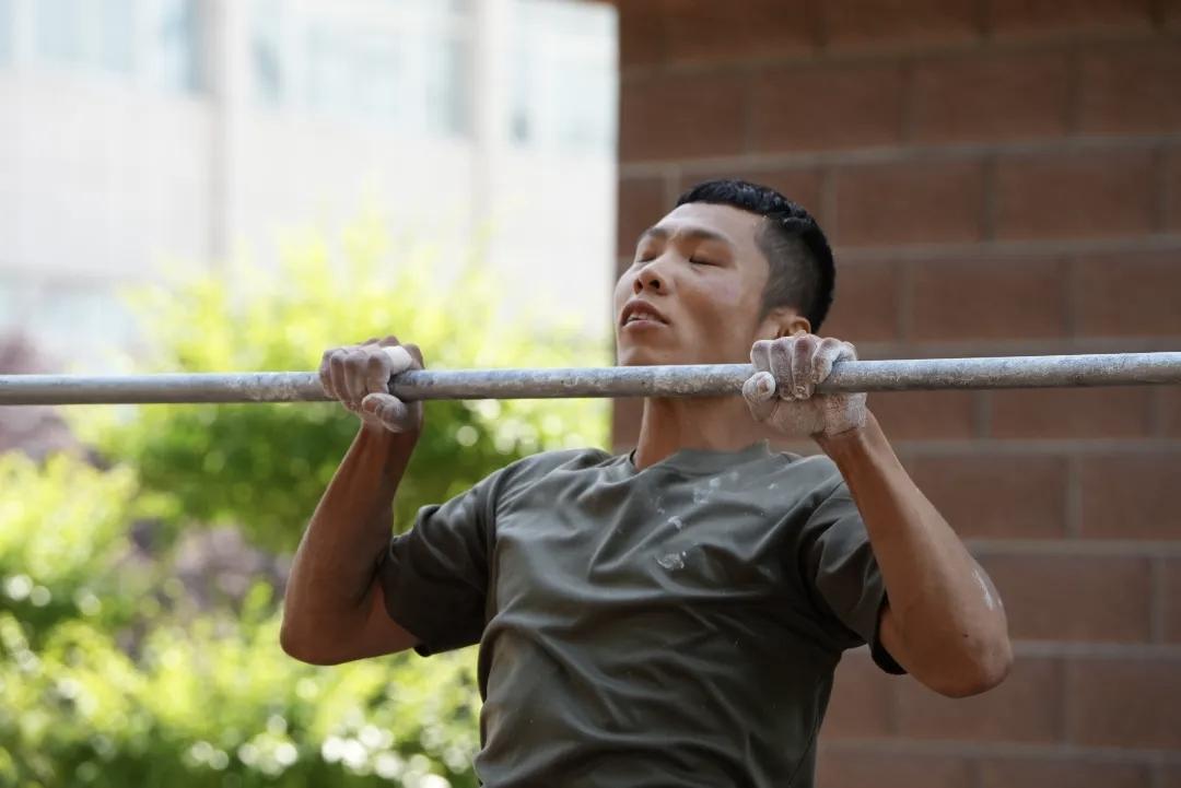单杠上，中士杨光明的双手早已磨出血泡，身体仍在一次次拉起、放下。考核现场的数数声