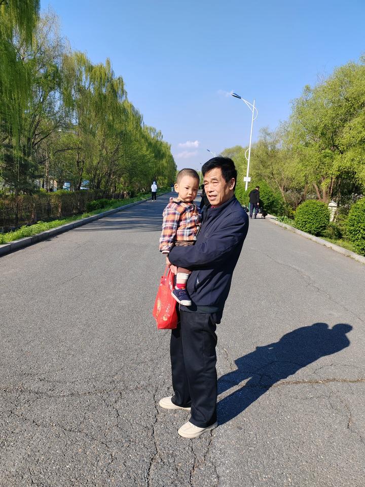 我今天和老头子带孙子到铁岭柴河大堤上留达，我用手机拍下了爷爷抱着孙子的留影纪念。