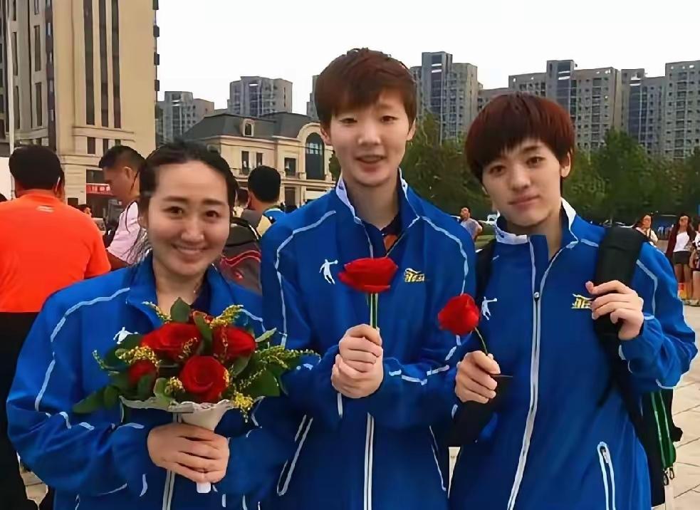 三位女乒球员手持玫瑰花同框：

我只认出了身材高挑、柔发覆额的奥运会冠军王曼昱与