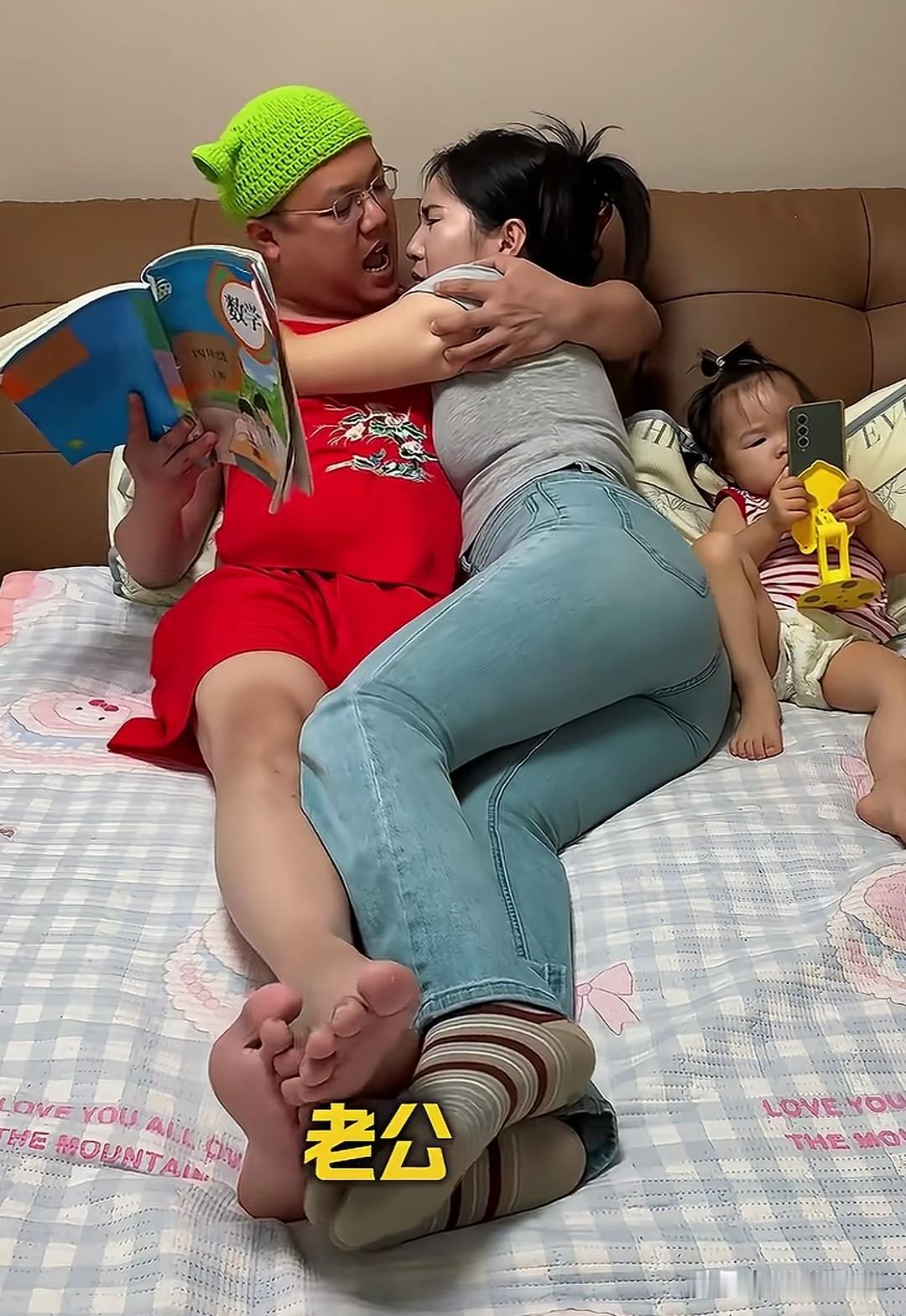 这两夫妻在干嘛，老公手里拿着一本数学课本，戴着一顶绿帽子，穿着红色裙子，到底在干