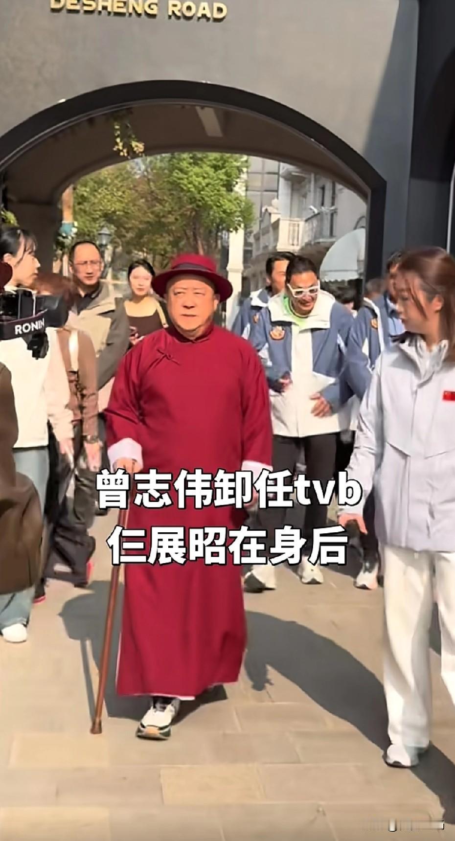 红长衫红礼帽拄着拐杖‌，一副大佬气派。年轻时演一些搞笑小角色，年纪老了很有气场。