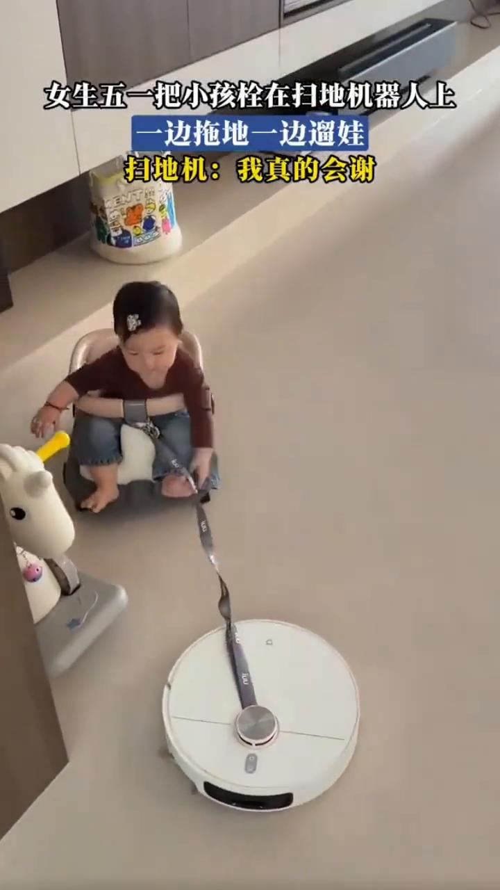 女生五一把小孩栓在扫地机器人上，一边拖地一边遛娃。扫地机：我真的会谢。
