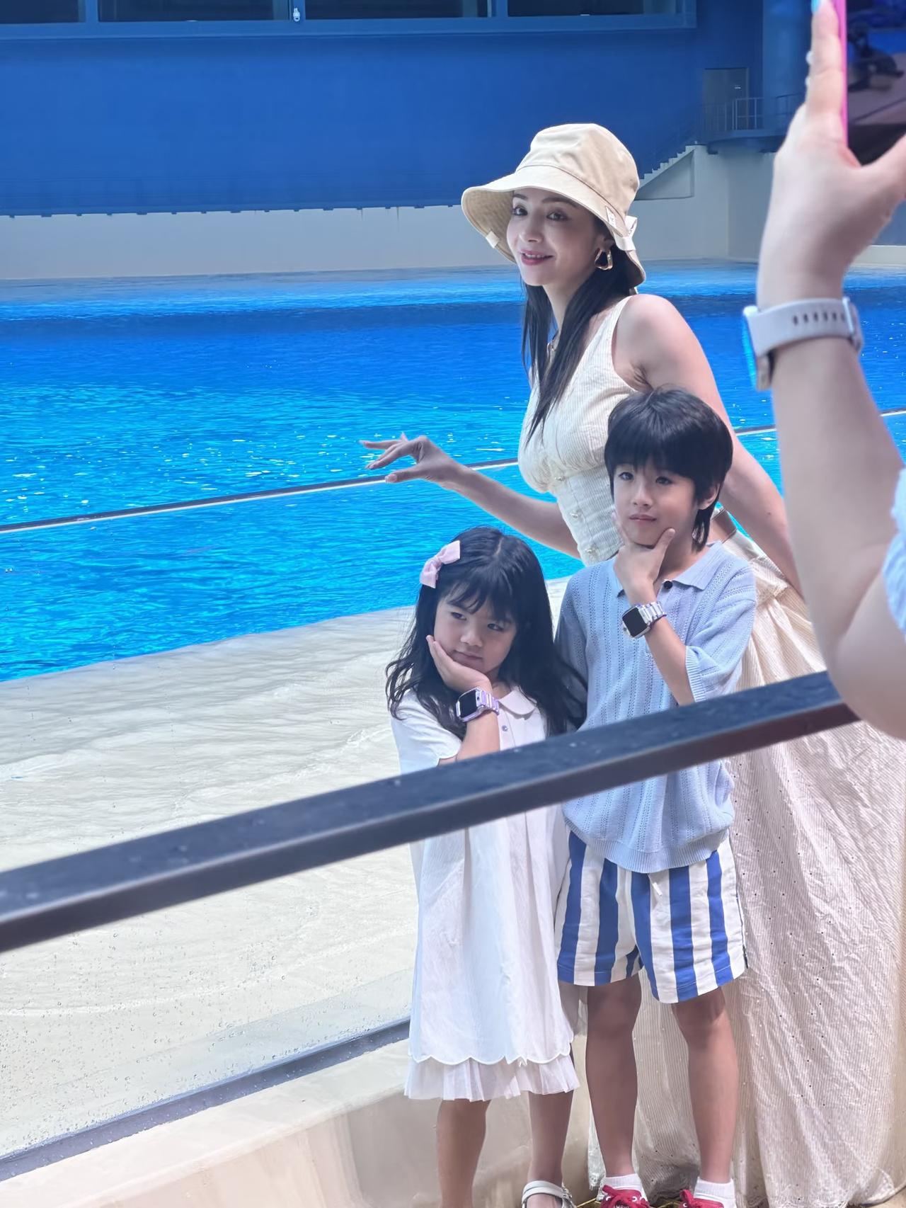 39岁麦迪娜带一对子女到珠海长隆海洋王国游玩，她穿着一条白色裙子，打扮贵气时尚，