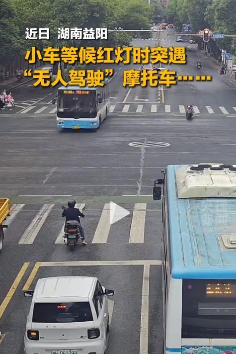实在反常！益阳城市主干道的路口上，监控画面里，这辆两轮摩托在车流中歪歪扭扭地向前