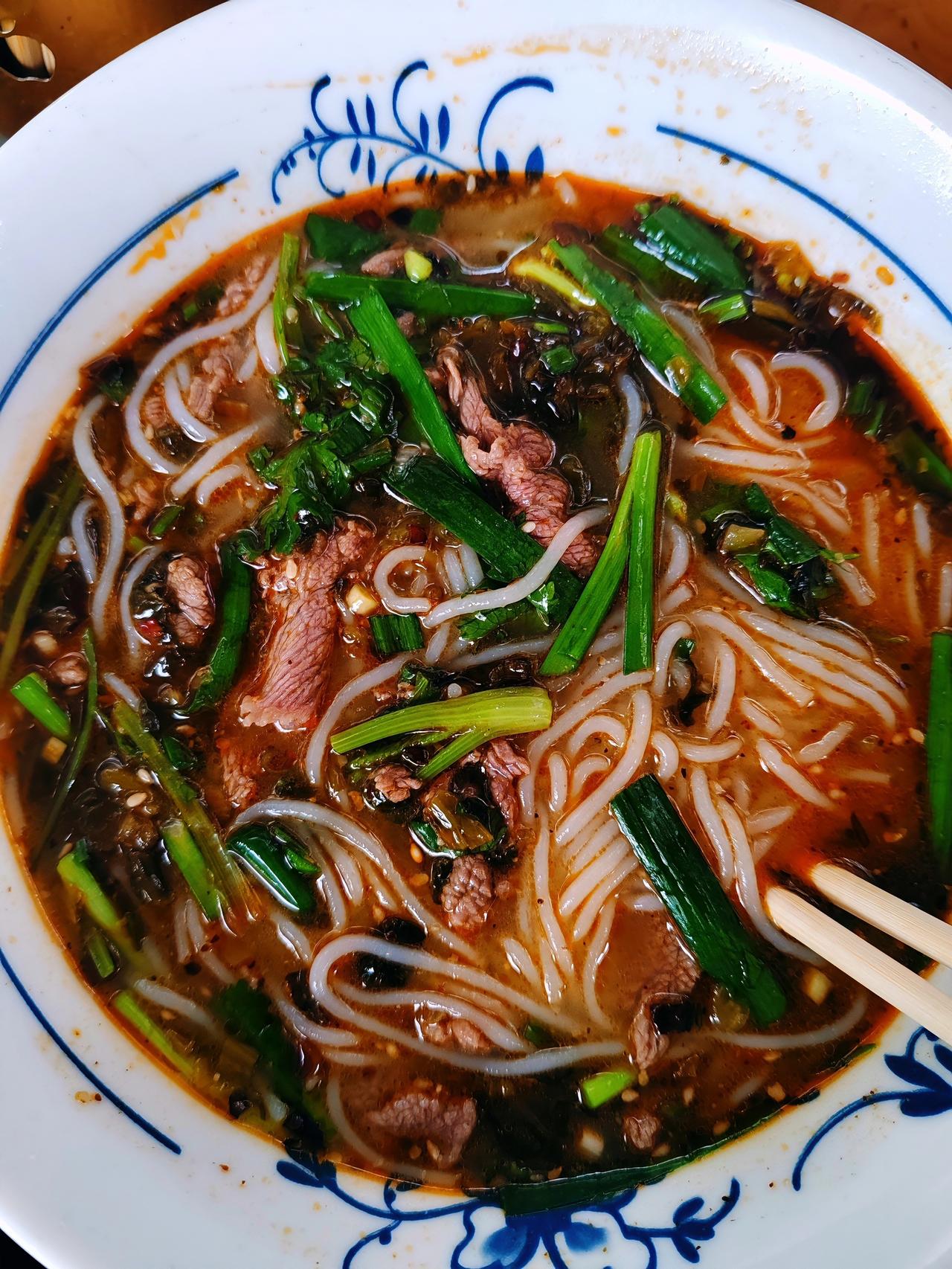 热气腾腾的牛肉米粉，鲜牛肉配上翠绿葱香，红汤浓郁，一口下去，满是地道家常滋味。