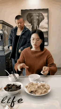 老婆在餐桌上放着刚做好的水饺，回头和老公说，坐下来吃点，老公晃动着身体摆头不吃，