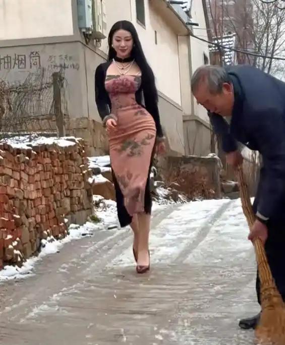 残雪还铺在乡间小路的地面上，寒气裹着乡村特有的安静。大爷拿着扫帚正在清扫路面，一