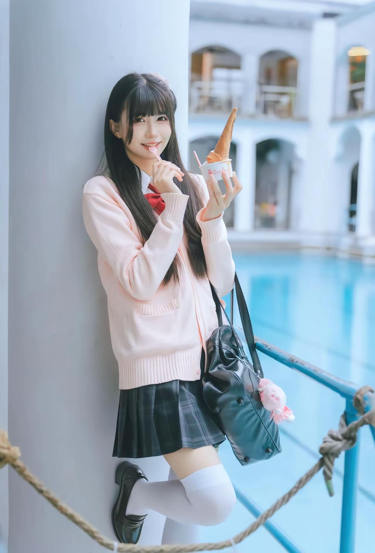 一个女孩靠在柱子旁，吃着冰淇淋。