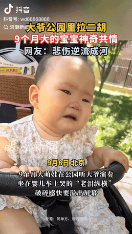 北京，一位宝妈推着9个月大的宝宝在公园散步，恰巧遇到一位大爷在拉二胡，不料宝宝听