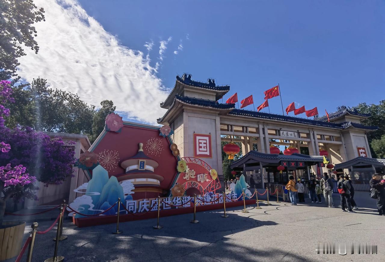 国庆佳节期间的天坛公园，鲜花绽放，红灯高掛，一派喜气洋洋的节日气氛，人们欢声笑语