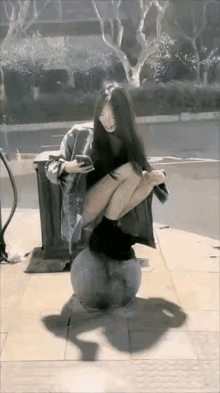 女孩站在表面光滑的圆圆的石球上拍视频，前一秒还在笑，可是几秒钟后，女孩就摔倒了，