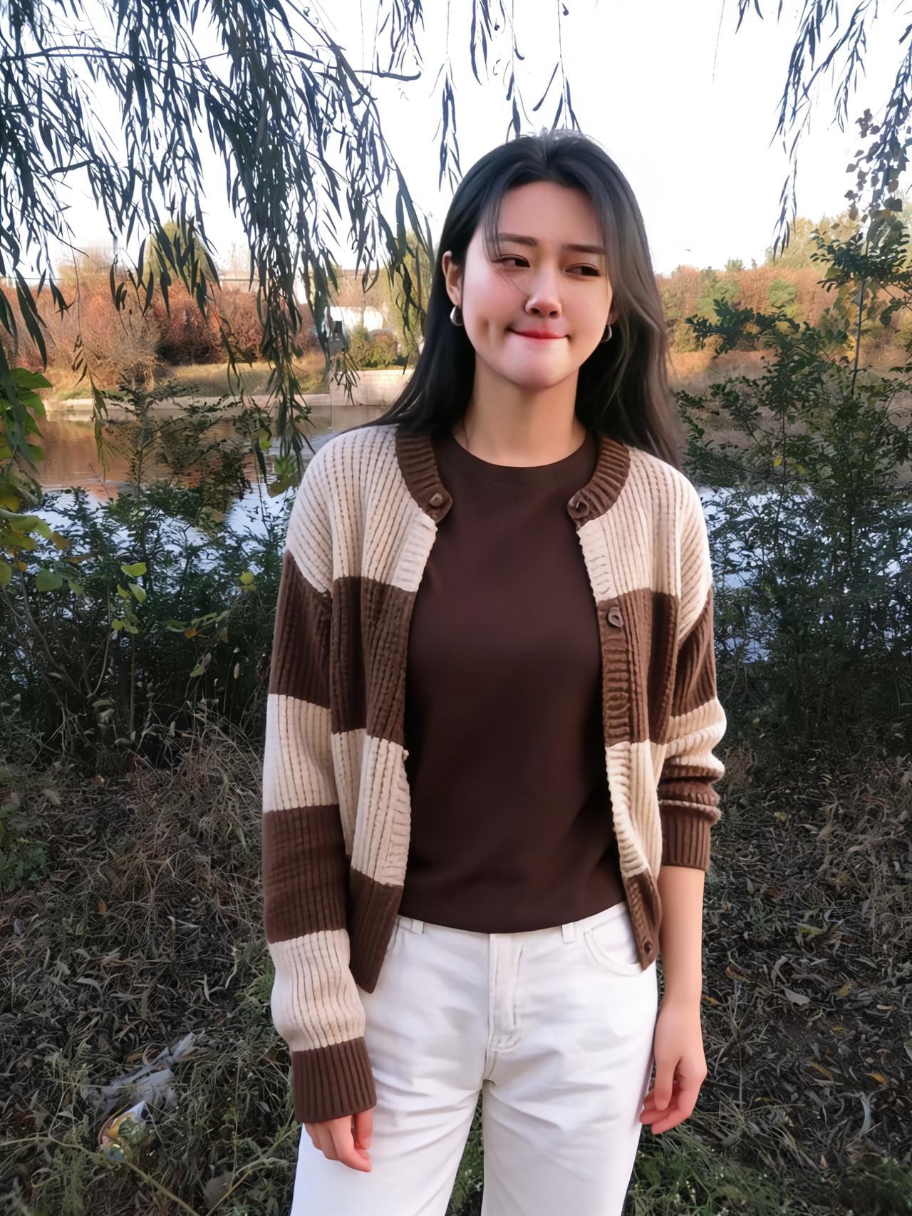 柳岸晴光映丽人，棕衫白裤衬清新。
开衫格纹凝秋韵，笑靥明霞染绛唇。
河水粼粼摇碎