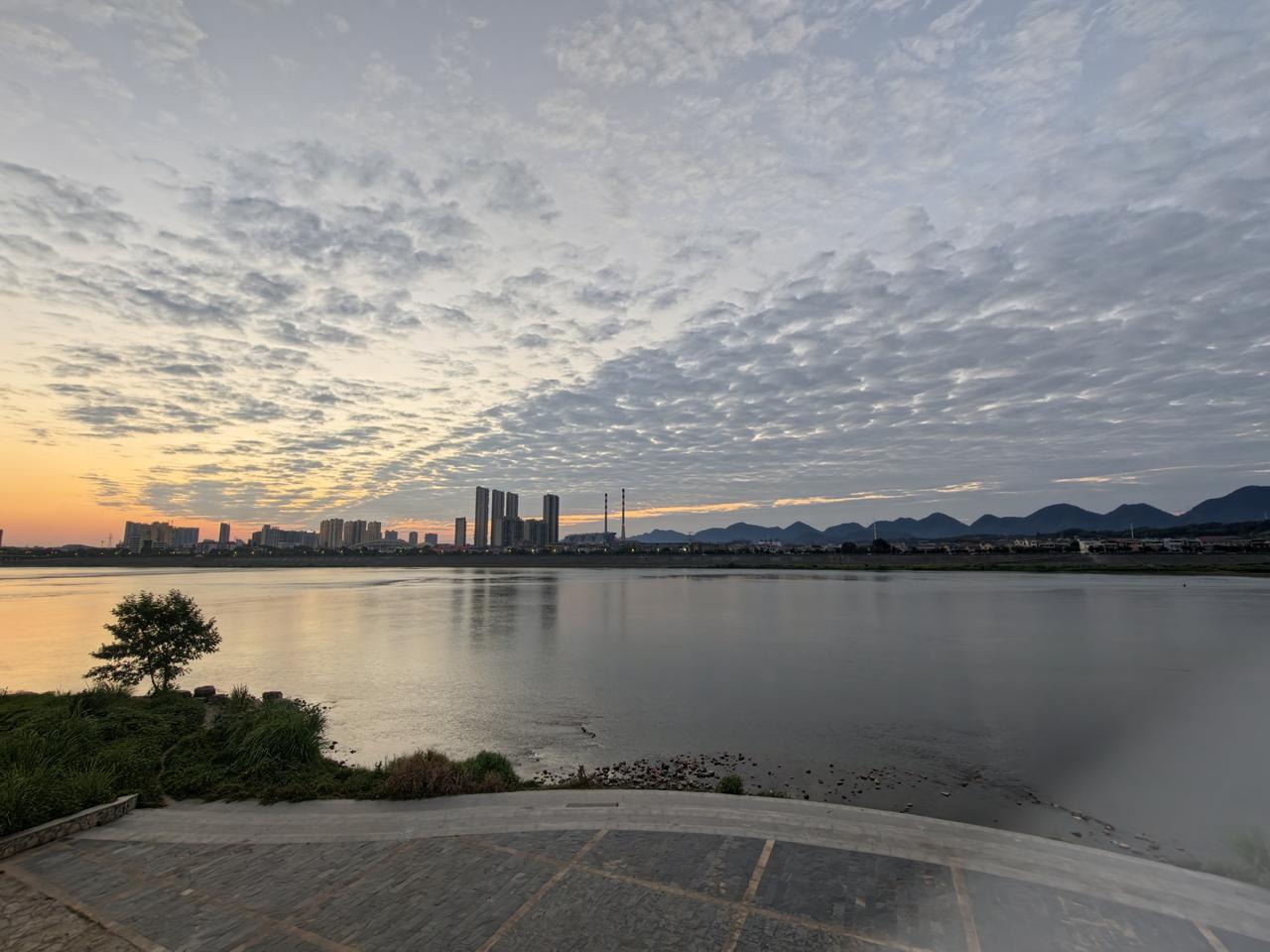 一江碧水静静流淌，远山连绵，云霞漫过天际。
从天色微蒙到落日染遍河畔，看江水映照