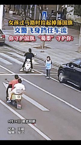湖北，一个小女孩放学过马路回家时，突然瞥见路中间飘着面国旗，她毫不犹豫的就冲了过