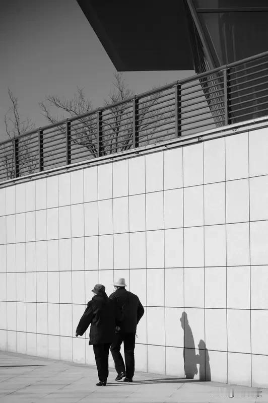 医院走廊尽头，一位大爷一动不动地坐着，脚下那双磨得皮发灰、缝线开口露出稻草的鞋子