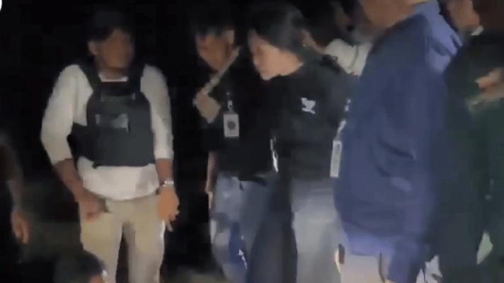 另一视频里柬埔寨抓捕在逃犯的现场，这个姑娘头发被人紧紧抓着、上着背铐，和其他男囚