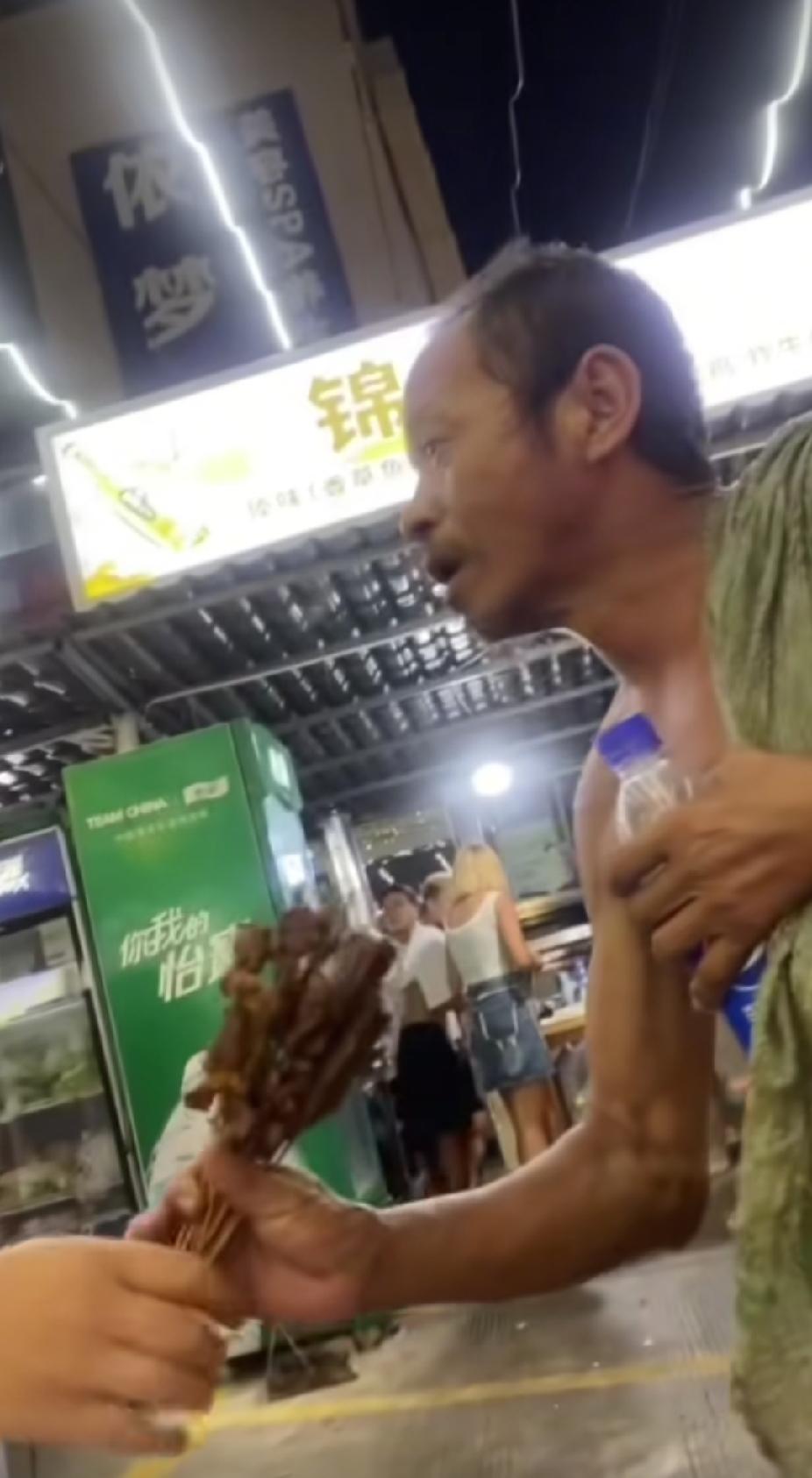 正在和朋友吃夜宵的小伙子，突然将盘子里的肉串全抓在手里，接下来的一幕，让人感动暖