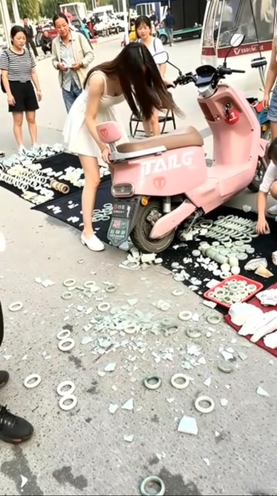美女摊上事了，骑电动车没能及时刹车，一下子给冲进路边的玉器翡翠摊，这下子不得赔个