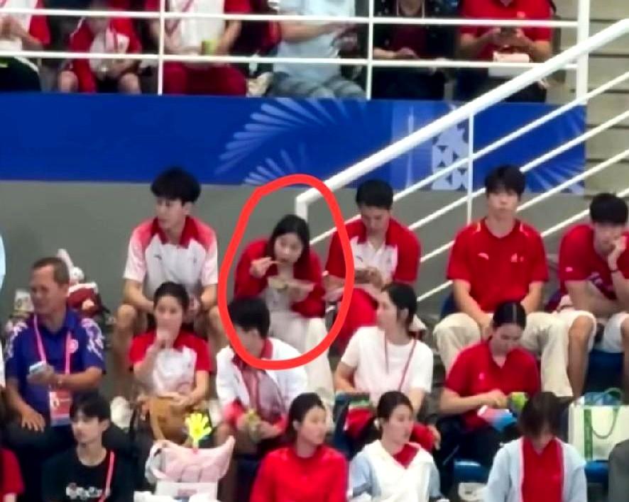 全红婵没上场，却抢了全场镜头。

她端着盒饭，蹲在观众席，为队友鼓掌的样子，比夺