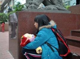 2011年3月的广州大道上，一位年轻母亲抱着六七个月大的女儿，膝盖贴着地面，一步