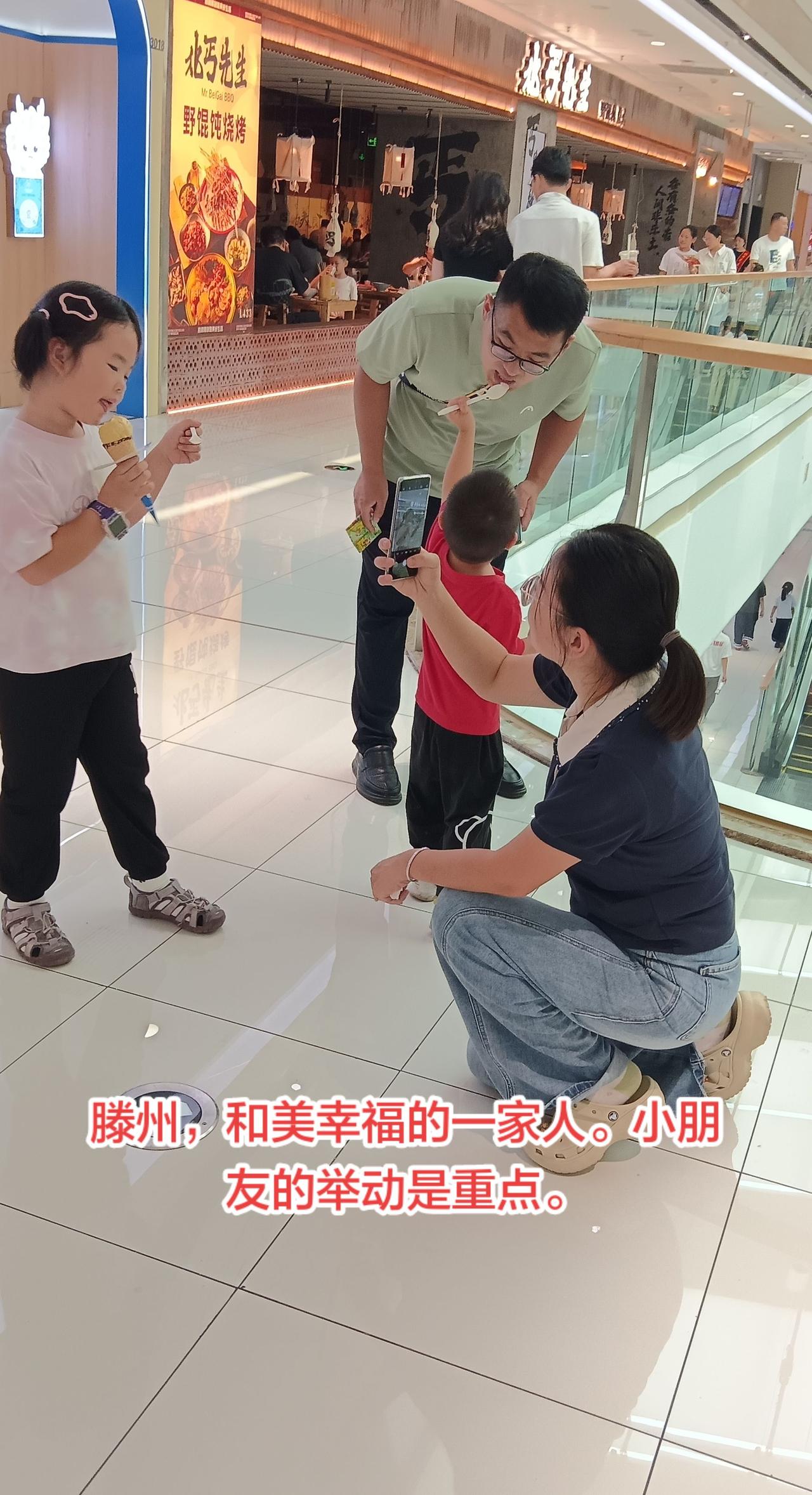 滕州，和和美美，幸福快乐的一家人。小朋友拿冰淇淋在给他爸爸吃，很懂得礼貌。一双儿