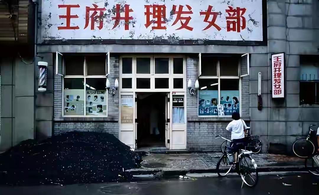 这张照片拍摄于八十年代，这是王府井的一家理发店，招牌上还写着“女部”，说明了这个