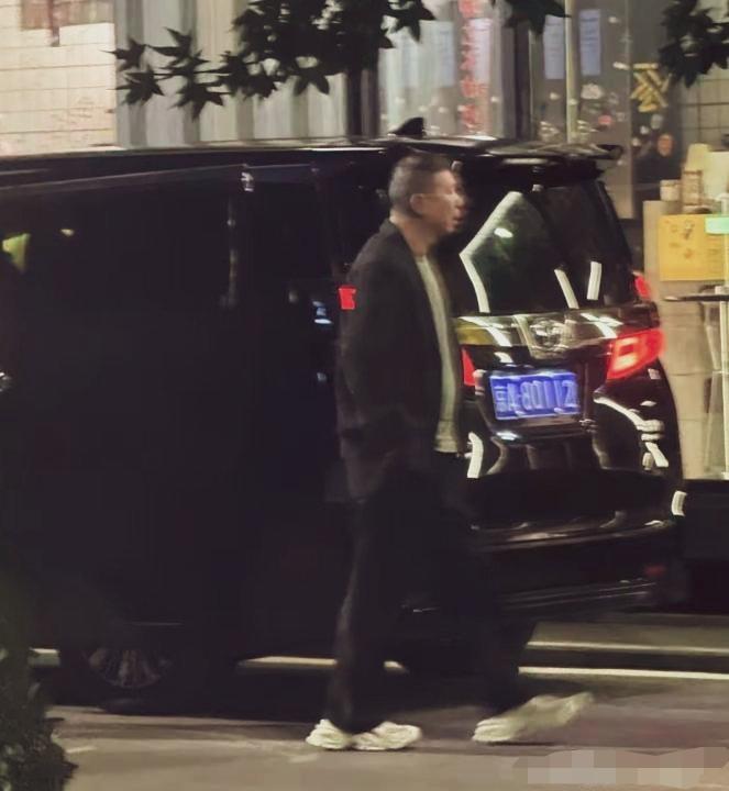 冯小刚夜晚街头路透，西装外套搭配休闲运动鞋，穿搭随性，结束工作离场，步履匆匆。