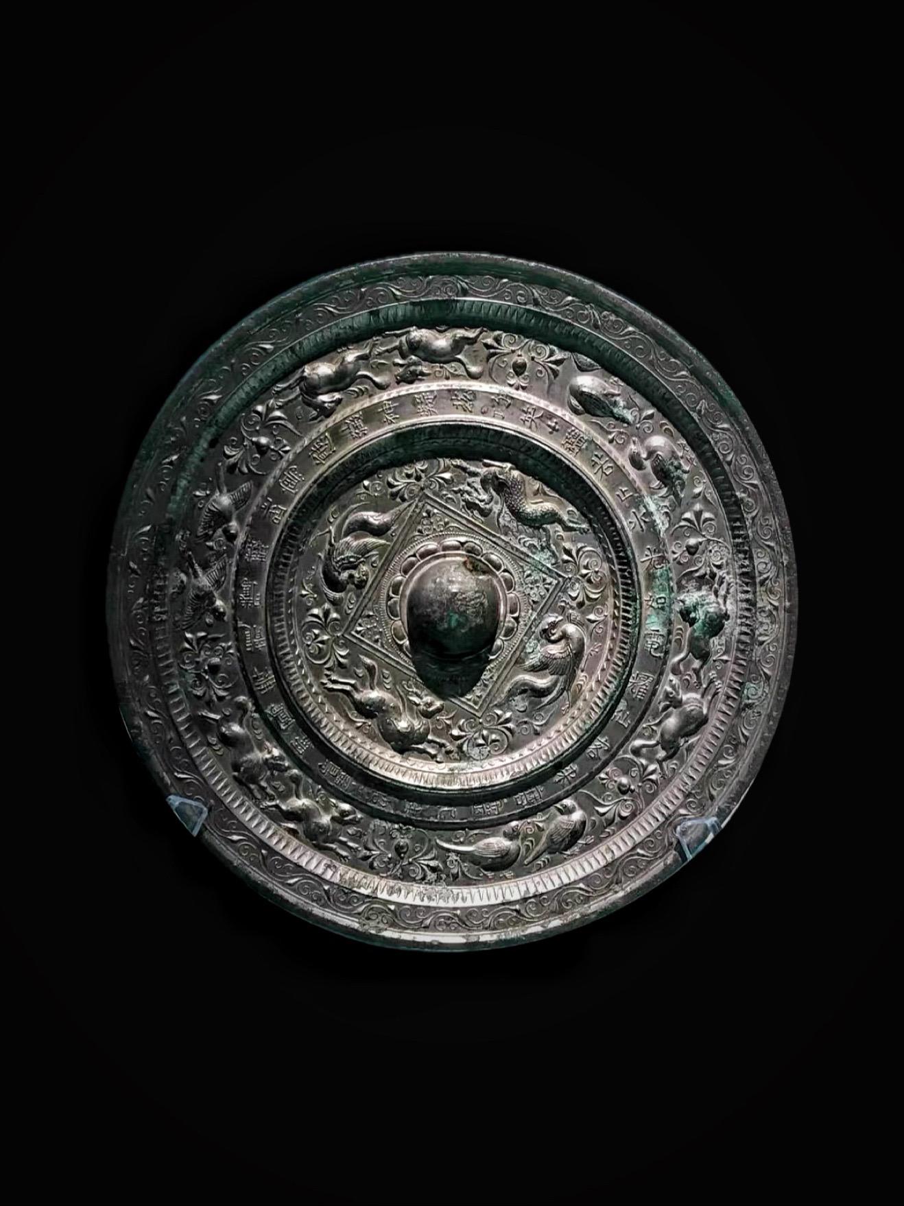 唐代·鉴若止水铜镜。彤史佳声载，青宫懿范留
形将鸾镜隐，魂伴凤笙游
送马嘶残日，新萤落晚秋
不知蒿里曙，空见陇云愁
——唐· 沈佺期《章怀太子靖妃挽词》 
该镜1971年出土于乾陵章怀太子墓，为圆形，厚胎平缘，直径24.5厘米，厚1.7厘米，重4.26千克，有修复痕迹 ，是章怀太子李贤与妃子房氏合葬墓中的陪葬明器，乾陵博物馆藏 
镜背面纹饰分为内外两区
内区，中心为半球形钮，钮上穿绶用的孔直径1.1厘米
钮座周围，饰有一圈宝相莲珠乳丁，外有双线方格
格内，四角饰蔓草
格外，青龙、鸾鸟、麒麟、凤凰分踞四方，呈