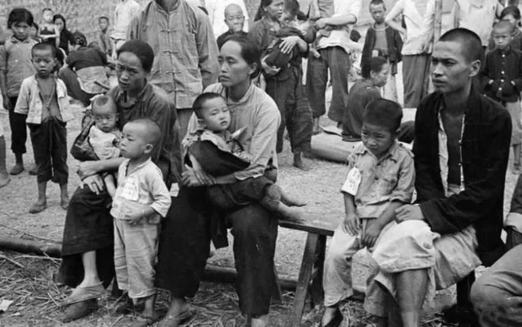 民国时期的一张老照片，一群衣衫褴褛的穷苦人正在集市上看玩把戏的，一个小男孩的裤子