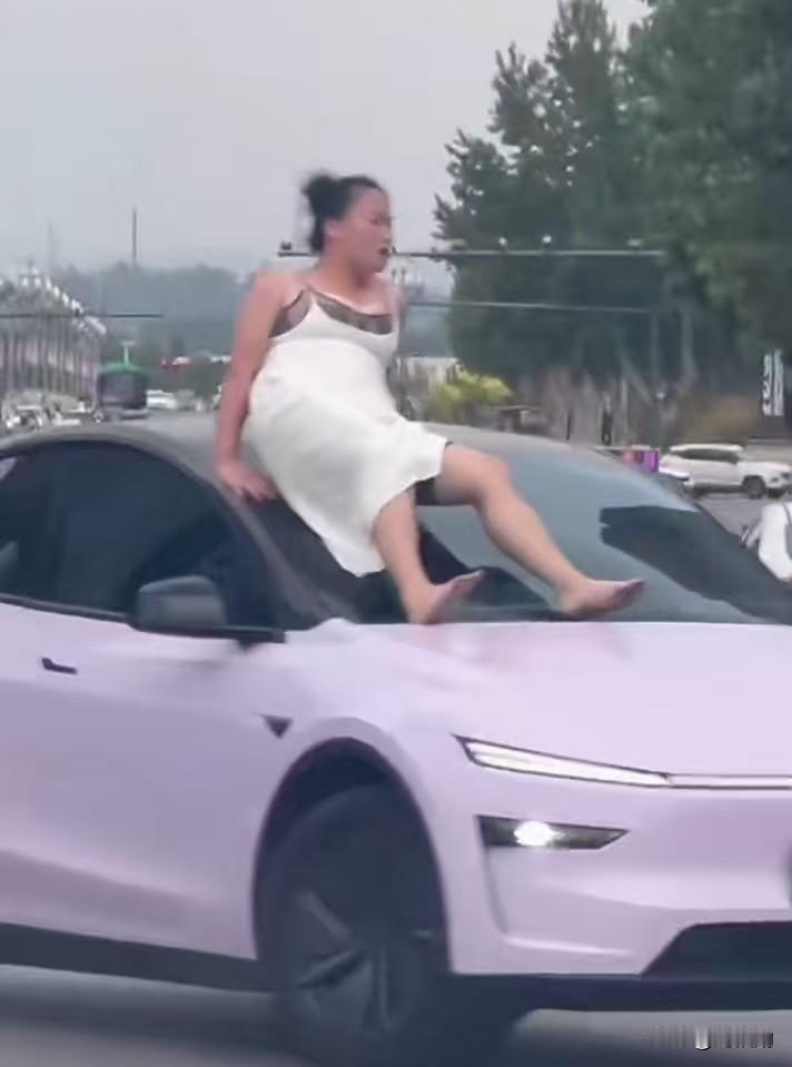 路口车流排起长龙，一名身着白裙的女子赤脚站在粉色轿车引擎盖上，拥堵的马路瞬间陷入