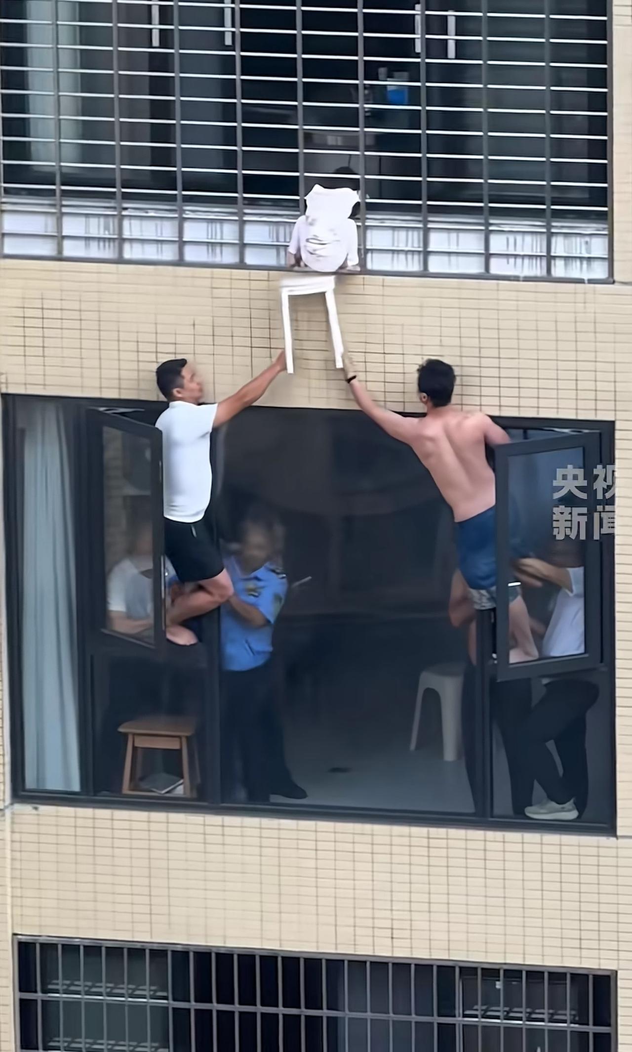 隔着楼层高空接力递凳子，看得人手心直冒汗！两个大哥半个身子探出窗外，小心翼翼托着