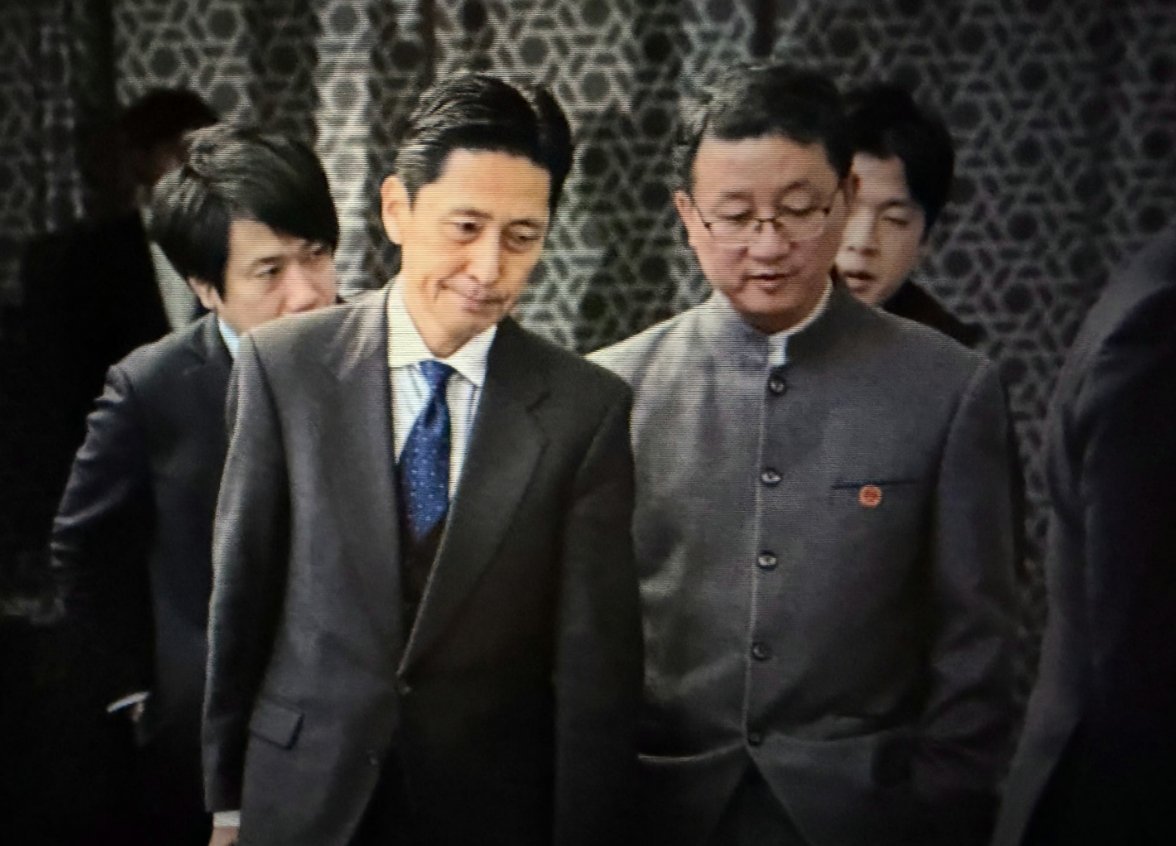 中国外交部亚洲司司长刘劲松五四青年装配戴国徽双手插兜表情轻松，小本子一脸凝重……