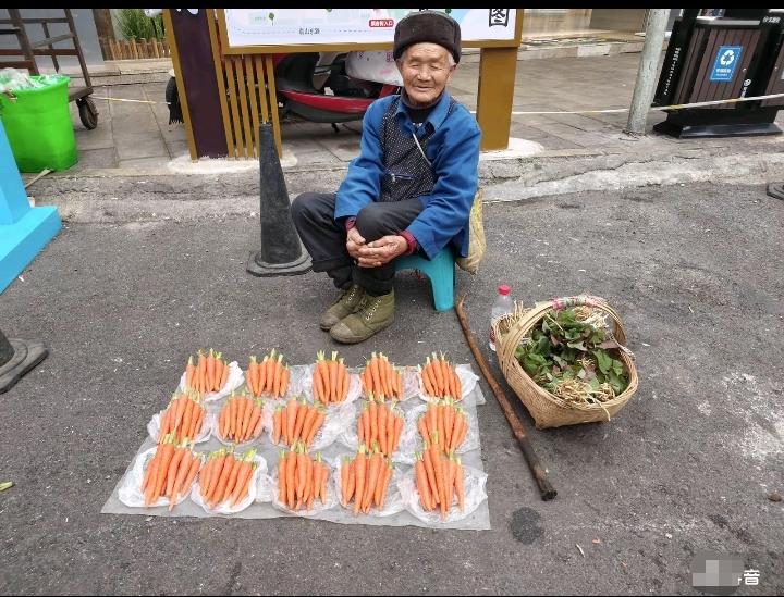 一个人对生活的态度从他的面相和穿着中就一目了然！一位慈祥的爷爷在路边卖红萝卜！他