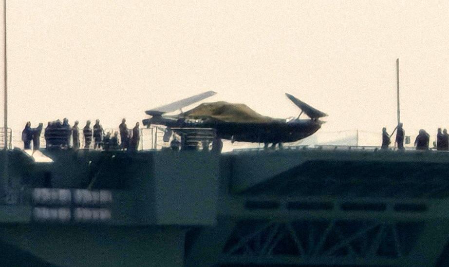 076舰甲板上的无人攻击机开始逐渐露出真面目，在这张照片里，机翼上包裹的蒙布已经