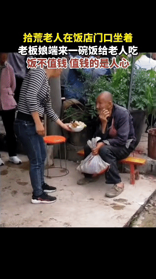 饭店门口，一位拾荒老人静静坐着。老板娘瞧见后，暖心地端来一碗饭递给老人。老人满是