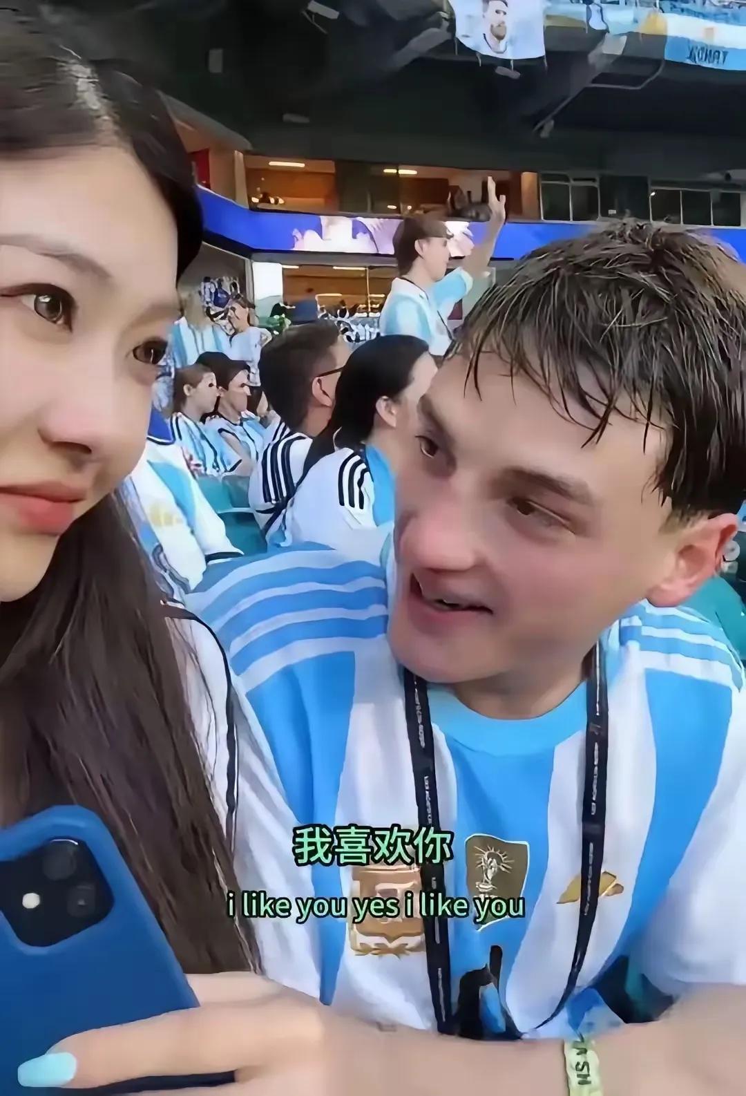 一名国内的女孩在世界杯现场被阿根廷男孩求婚，女孩旁边坐着一个阿根廷的男生，男生对