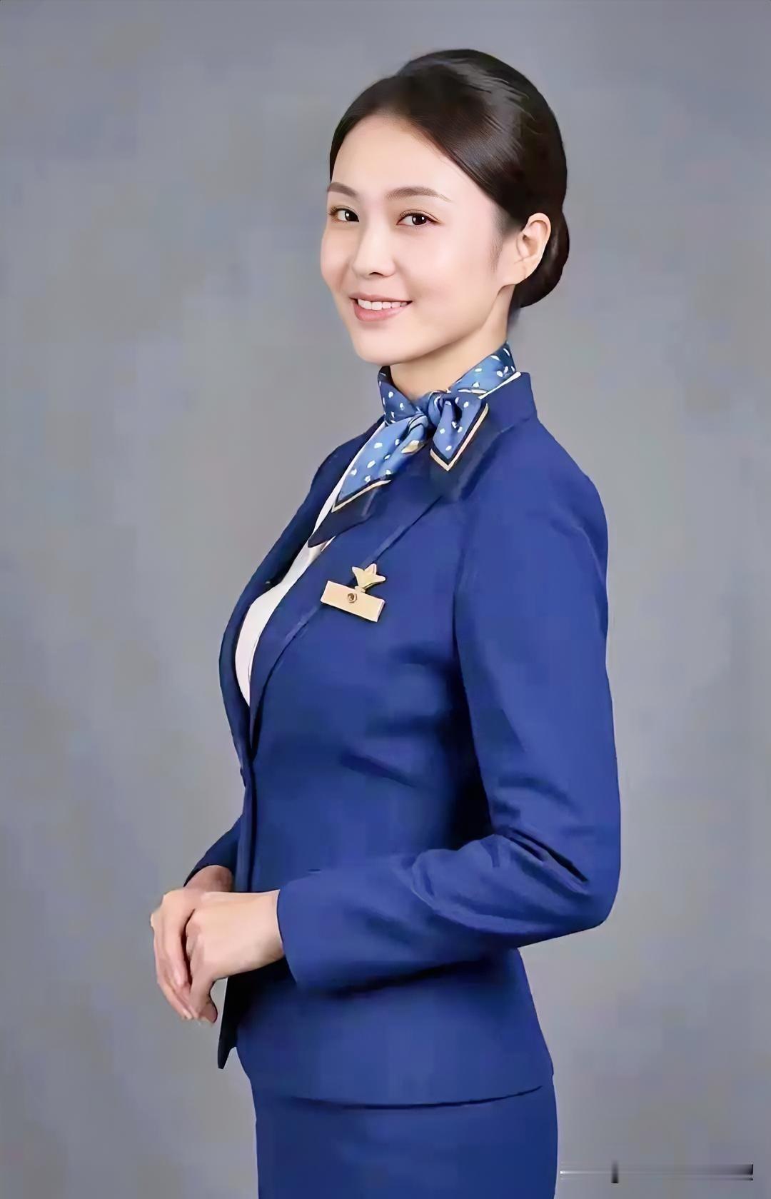 藏蓝制服勾勒出端庄的身姿，浅蓝丝巾点缀着优雅的颈间。温婉的笑靥如春风拂面，清澈的